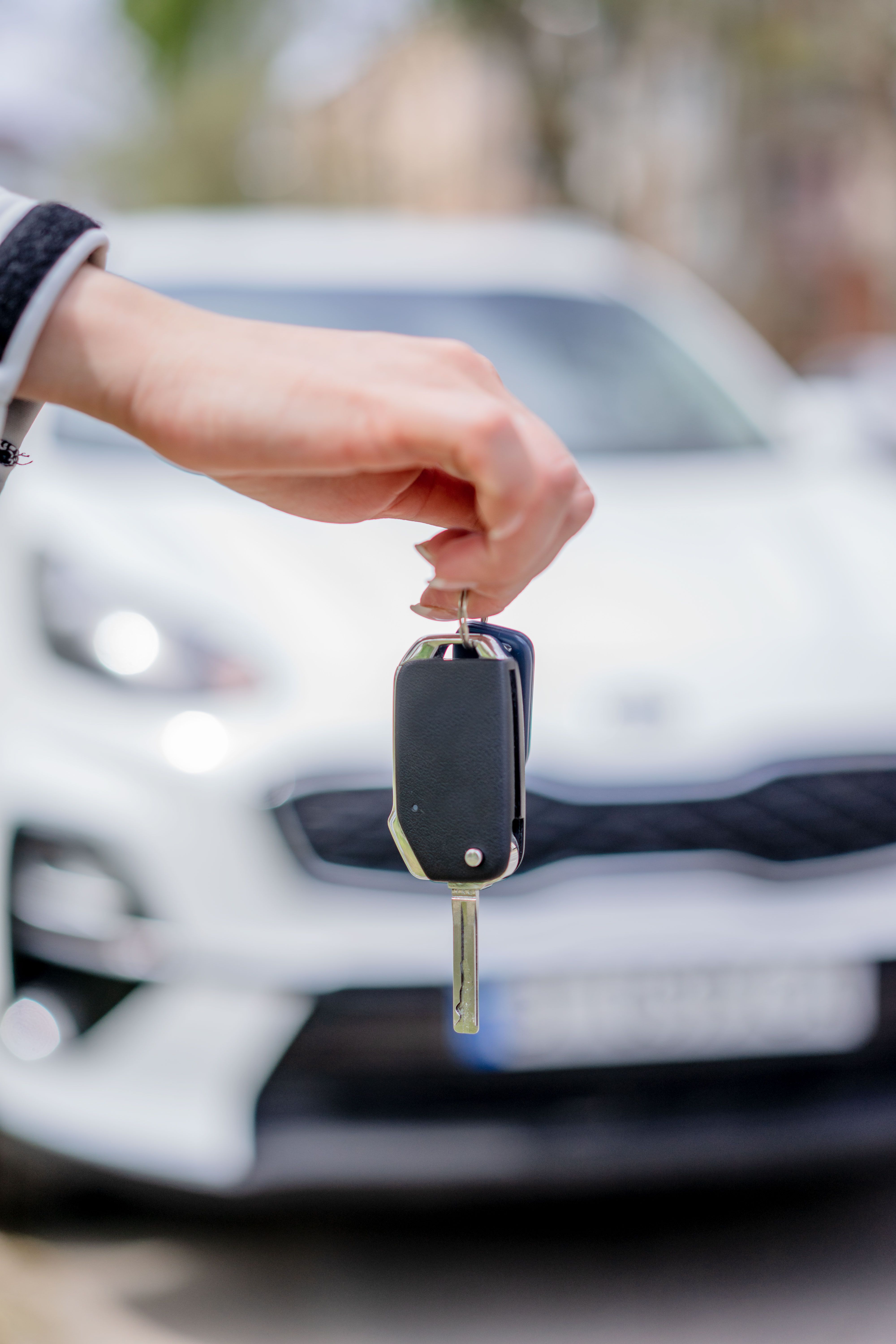 Handing over car rental keys in front of a white car